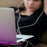 Woman-using-a-laptop-on-top-of-a-sofa