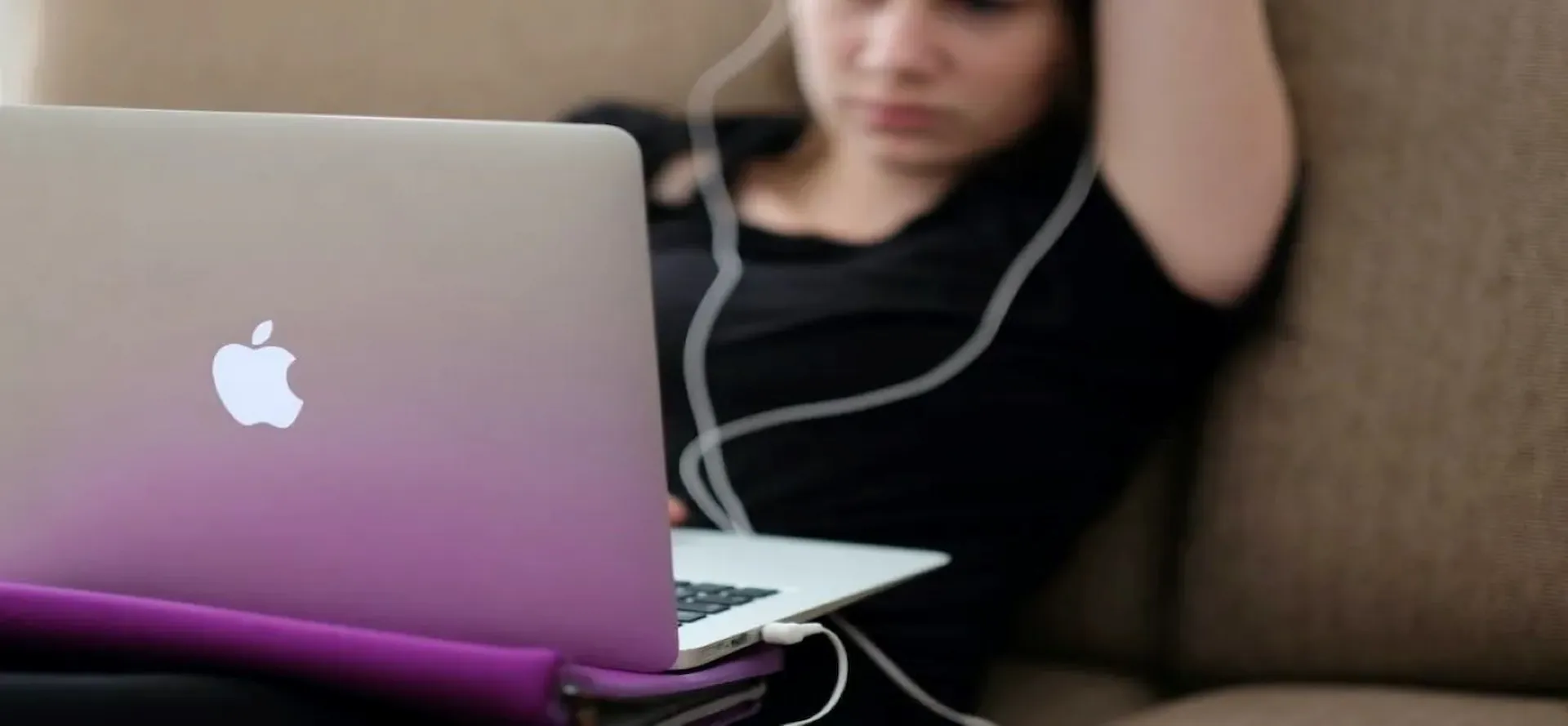 Woman-using-a-laptop-on-top-of-a-sofa