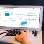 A person working on a laptop with graphs