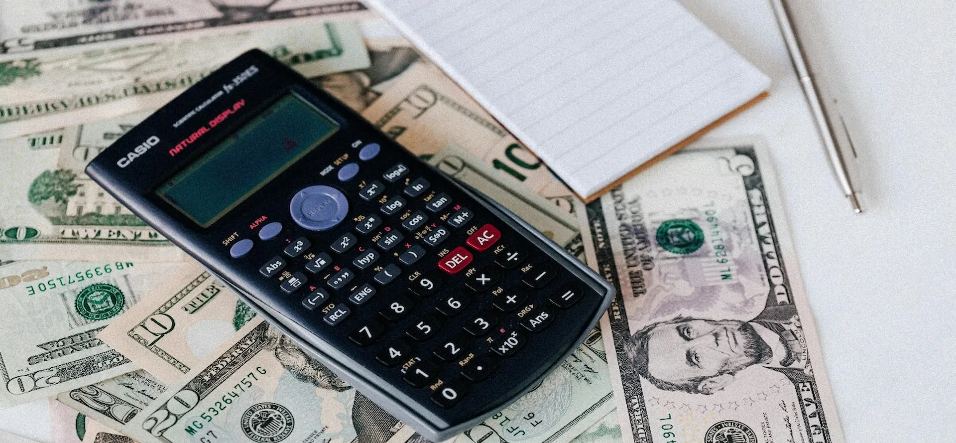 A notebook and a calculator on top of ten dolllar bills