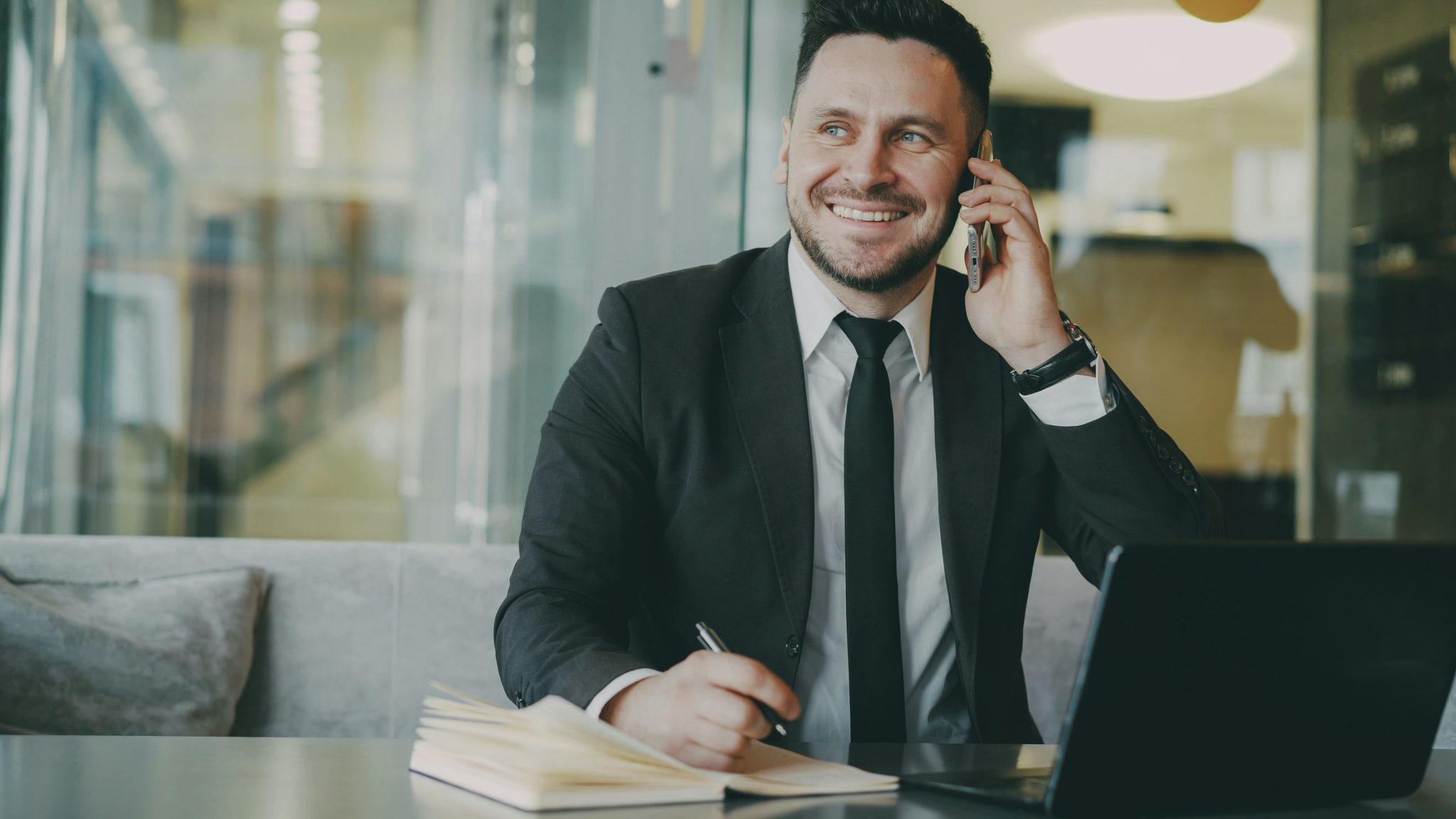 Professional talking on the phone while reviewing job opportunities in a modern office environment